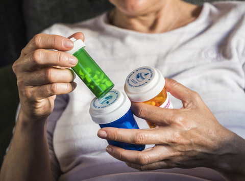 Woman examining medication treatment, several boats in the hand, conceptual image